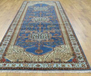 A long blue and beige patterned runner rug displayed on a hardwood floor by Khazai Rugs in Lexington, KY