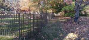 A long brown aluminum fence installed in a spacious backyard with autumn leaves, by Chesley Fence & Deck in Fairview Heights, IL.
