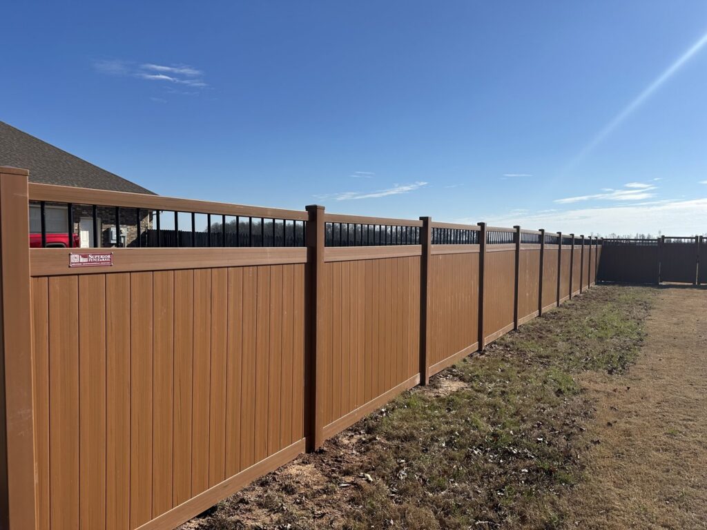 A long brown composite fence with black decorative top rails installed by Superior Fence and Rail of Little Rock, AR