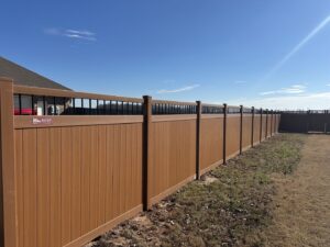 A long brown composite fence with black decorative top rails installed by Superior Fence and Rail of Little Rock, AR