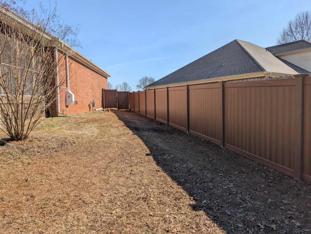 A long brown composite fence installed along a property line by Alabama's Fencing in Huntsville, AL.