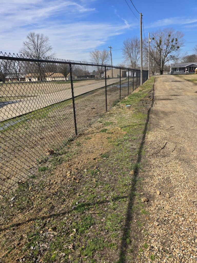 A long, durable chain-link fence installed along a dirt path by The Fence Man in Fort Smith, AR.