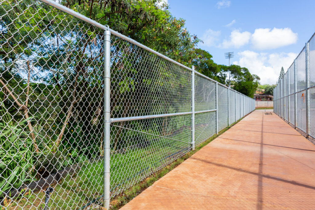 A long chain-link fence installed alongside a pathway by Upright Fencing Hawaii LLC in Kapolei, HI.
