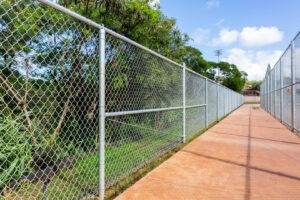 A long chain-link fence installed alongside a pathway by Upright Fencing Hawaii LLC in Kapolei, HI.