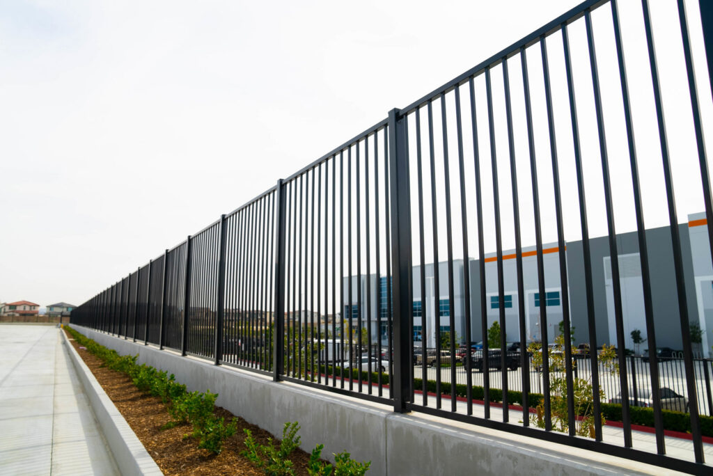 A long commercial black metal fence installed along a sidewalk next to a building by Competitive Fence Contractors LLC in Scottsdale, AZ.