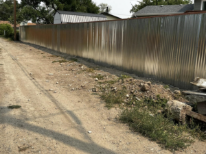 A long corrugated metal fence installed along a dirt path by Tomahawk Fencing in Riverton, WY.