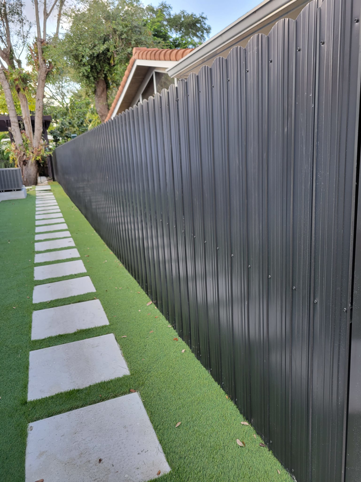 A long view of a dark gray corrugated metal fence installation by Southeastern Fence Corp. in Pembroke Pines, FL.