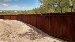 A long, curved rustic corrugated metal fence installed by Fence Company Tucson in Tucson, AZ.