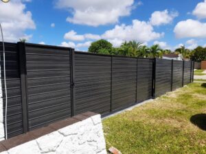 A long dark metal horizontal slat fence with an integrated gate, installed by Allende J. Service Corp in Miami, FL.
