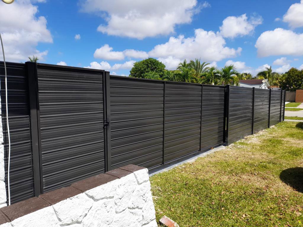 A long dark metal horizontal slat fence with an integrated gate, installed by Allende J. Service Corp in Miami, FL.