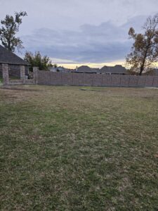 A long decorative stone-look fence installed in a residential area by 5-Alarm Fence Company in New Orleans, LA.