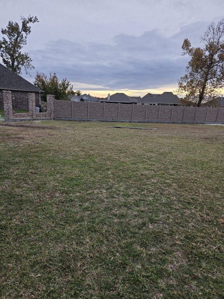 A long decorative stone-look fence installed in a residential area by 5-Alarm Fence Company in New Orleans, LA.