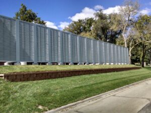 A long gray louvered fence installed on a retaining wall by American Fence Company - Omaha in Omaha, NE.