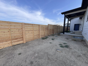 A long stretch of new horizontal slat wooden fence enclosing a backyard by Nailed It Fencing in Williston, ND.