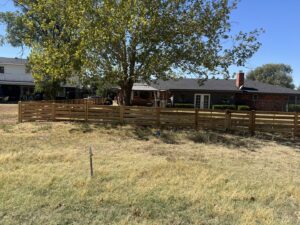 An extensive horizontal slat wooden fence installed across a large residential yard, a project by DC Fencing LLC in Clovis, NM.