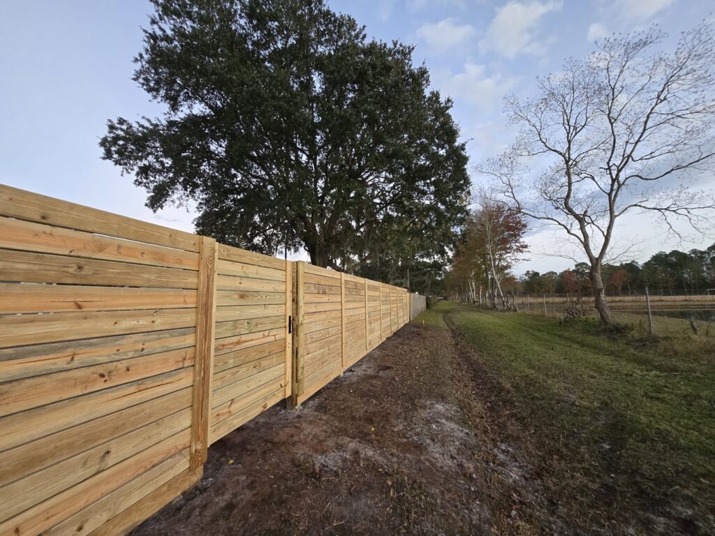 A long horizontal wood fence extending along a rural path, installed by Masters Fence Contracting in Jacksonville, FL.