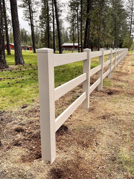 A long line of light-colored multi-rail ranch fence extending into the distance by BKC Fencing in Spokane, WA.
