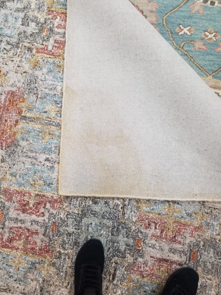 A long, decorative runner rug with a traditional pattern laid out on a hard floor at Dave's Magikist, Inc. in Milwaukee, WI.