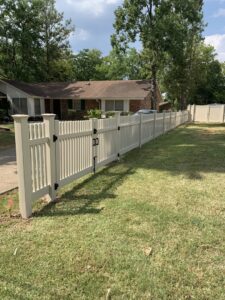A long, light-colored picket-style vinyl fence with a gate in a residential front yard by Pride Fence LLC in Overland Park, KS.