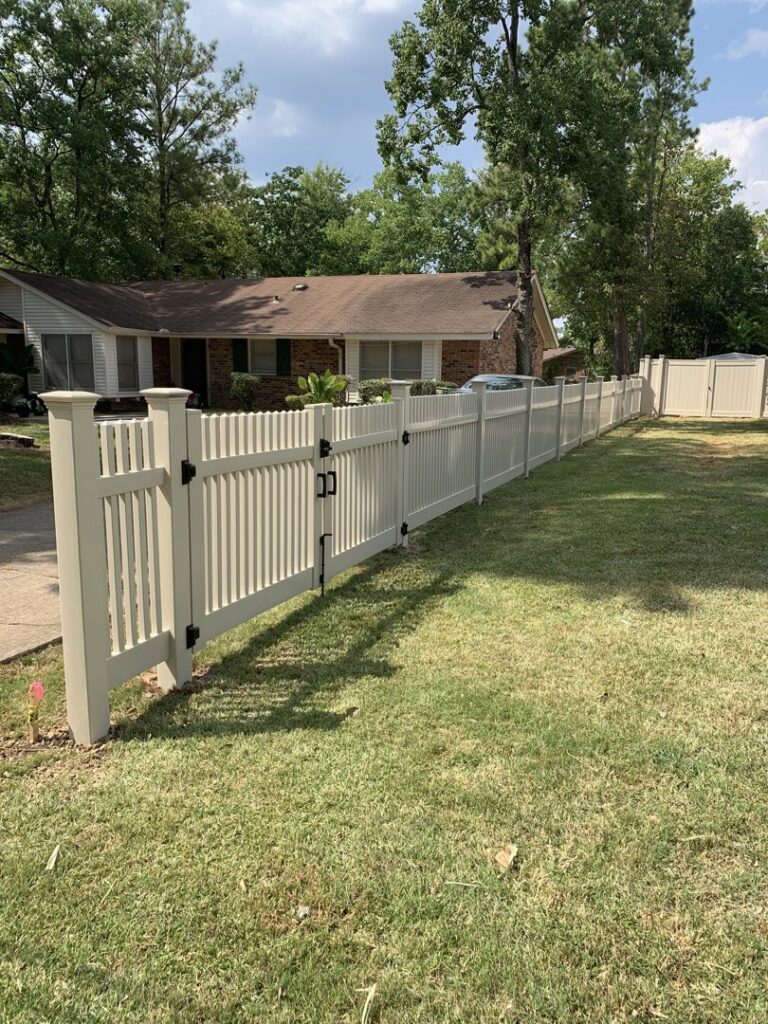 A long, light-colored picket-style vinyl fence with a gate in a residential front yard by Pride Fence LLC in Overland Park, KS.