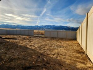 A long privacy fence with a gate, extending into the distance with mountains in the background by All Over Fence Idaho in Jerome, ID