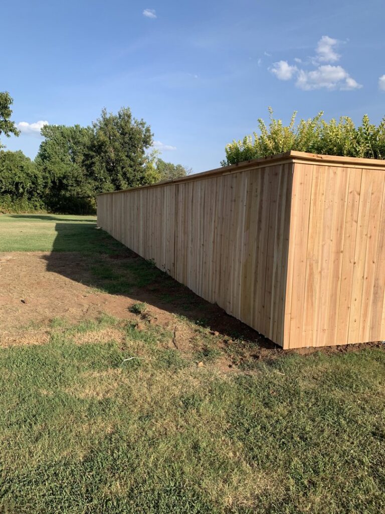 A long, newly installed wooden privacy fence in a residential setting by TOP TIER FENCE LLC in Oklahoma City, OK.