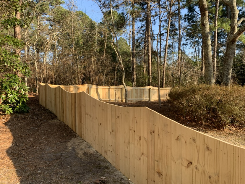 A long section of scalloped natural wood privacy fence installed by Brock Brothers Fence in Mobile, AL.