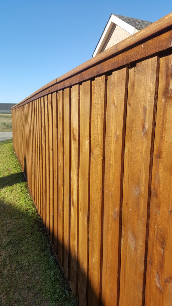 A long section of a newly stained wooden fence by Like New Fence Staining & Restoration in Plano, TX