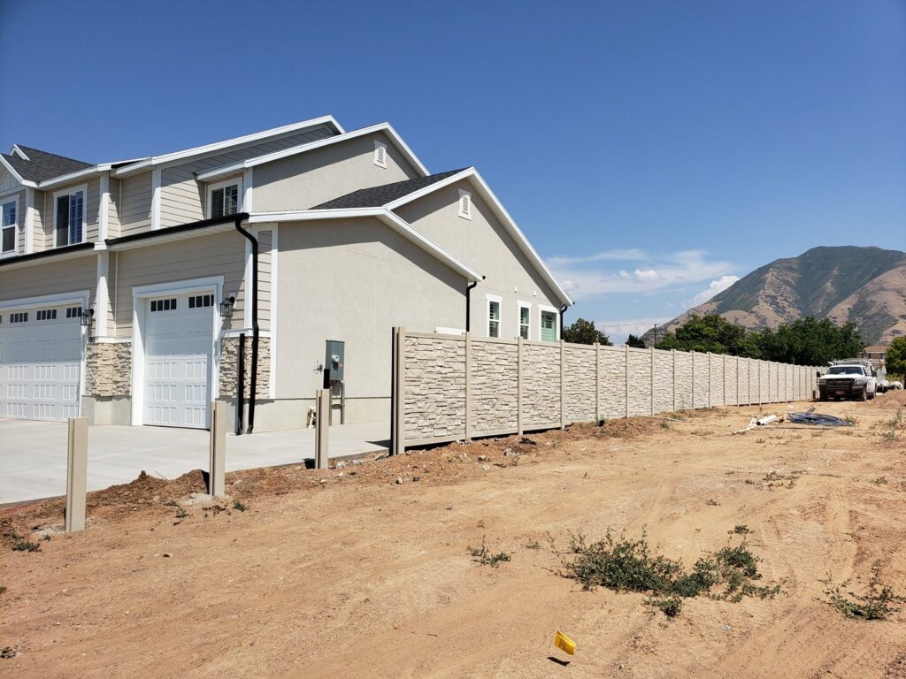 A long stone-texture fence installed alongside a new construction home by Stonehenge Fence & Deck in Orem, UT.
