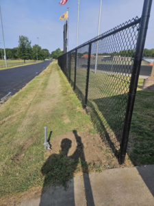 A long stretch of newly installed black chain-link fence running alongside a paved path by Atchison Fence in Effingham, KS.