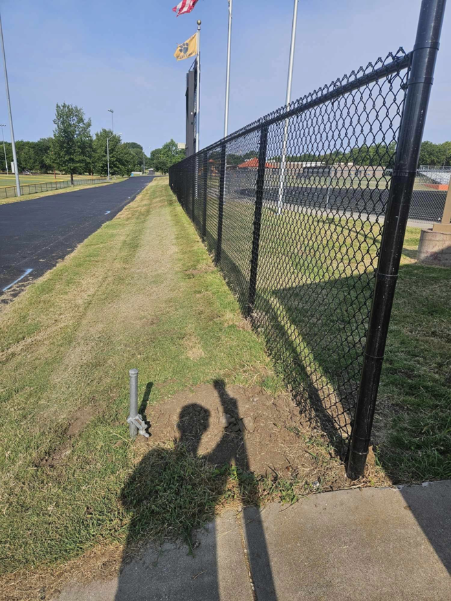 A long stretch of newly installed black chain-link fence running alongside a paved path by Atchison Fence in Effingham, KS.
