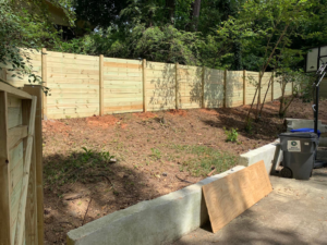 A long stretch of a newly installed wooden privacy fence along a sloped backyard by ETJ Fence and Restoration, INC. in Atlanta, GA.