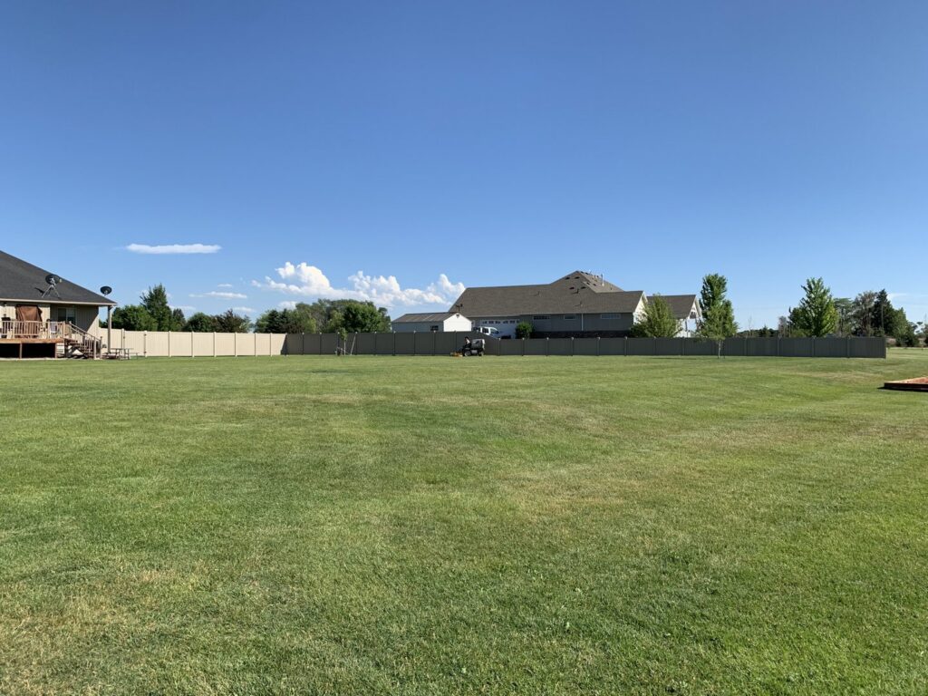 A long tan privacy fence enclosing a large residential backyard, installed by Idaho Falls Fencing in Idaho Falls, ID.