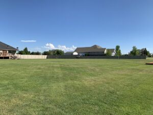 A long tan privacy fence enclosing a large residential backyard, installed by Idaho Falls Fencing in Idaho Falls, ID.