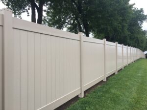 A long, tan vinyl privacy fence installed along a property line by Roy & Son Fencing in Lee's Summit, MO.