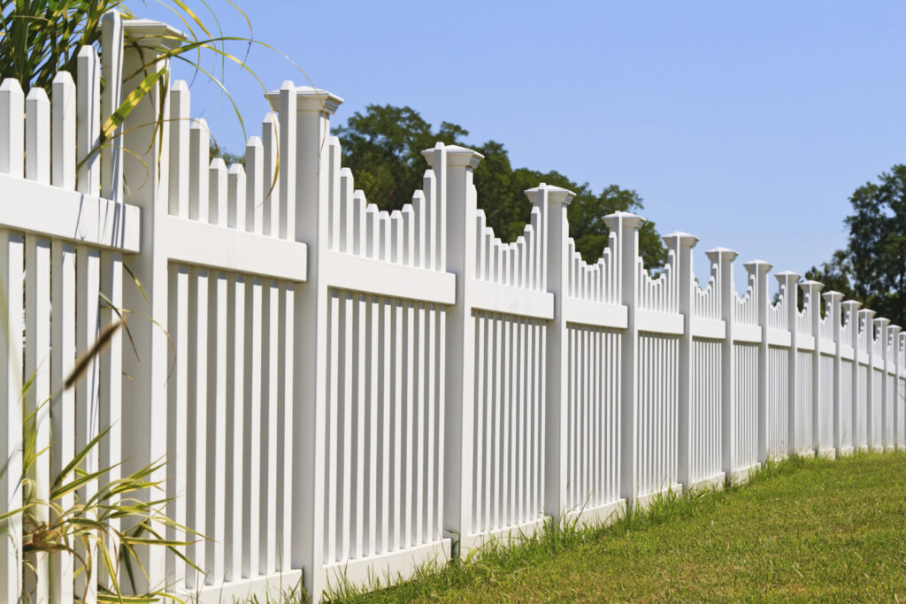 A long white picket-style fence installed along a property line by DZS Fencing, LLC in Red Lion, PA.