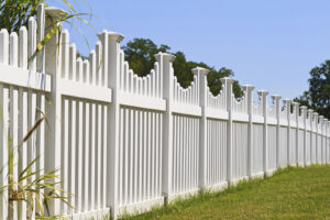 A long white picket-style fence installed along a property line by DZS Fencing, LLC in Red Lion, PA.