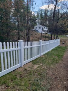 A long, classic white picket fence defining a property line, expertly installed by Sullivan & Sons Fence LLC in Hudson, NH.