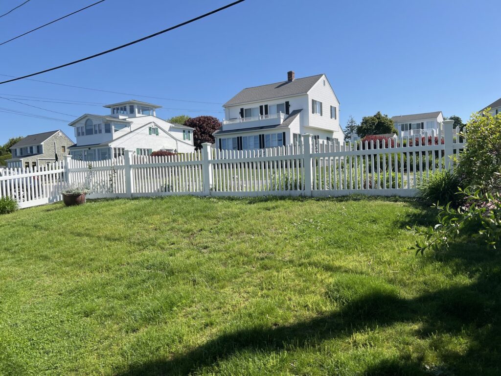 A long white picket fence installed in front of a residential lawn by Fence Company of Rhode Island in Providence, RI.