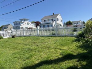 A long white picket fence installed in front of a residential lawn by Fence Company of Rhode Island in Providence, RI.