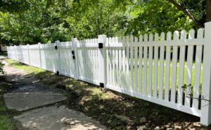 A long, classic white picket fence installed along a sidewalk by The Fence Man in Fort Smith, AR.