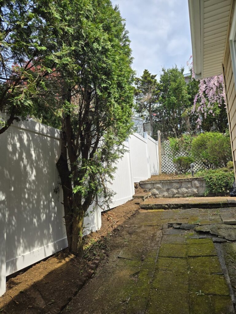 A long white vinyl privacy fence installed along a property line by Matul Fence Inc in Lynn, MA