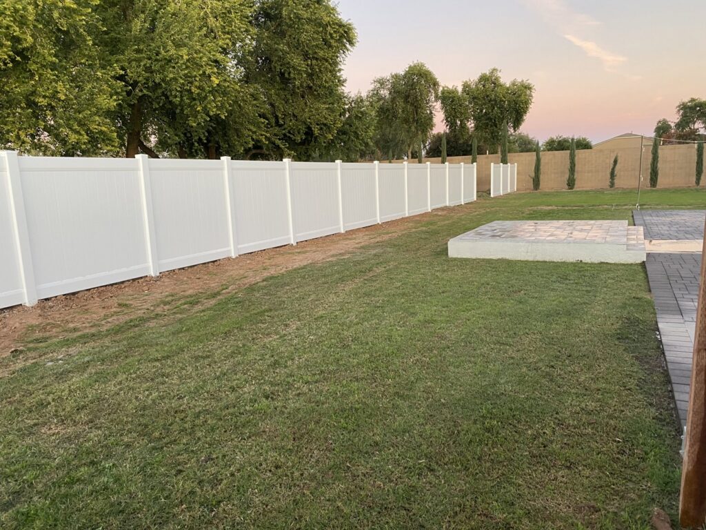 A long white vinyl fence installed in a residential backyard by Competitive Fence Contractors LLC in Scottsdale, AZ.