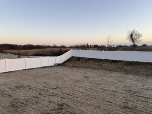 A long white vinyl fence installed in a residential backyard by Fence Connection, Inc. in Elgin, IL.