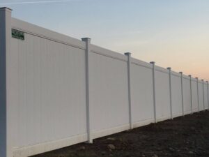 A long white vinyl privacy fence installed by Austintown Fence in Youngstown, OH, with their company sign visible.