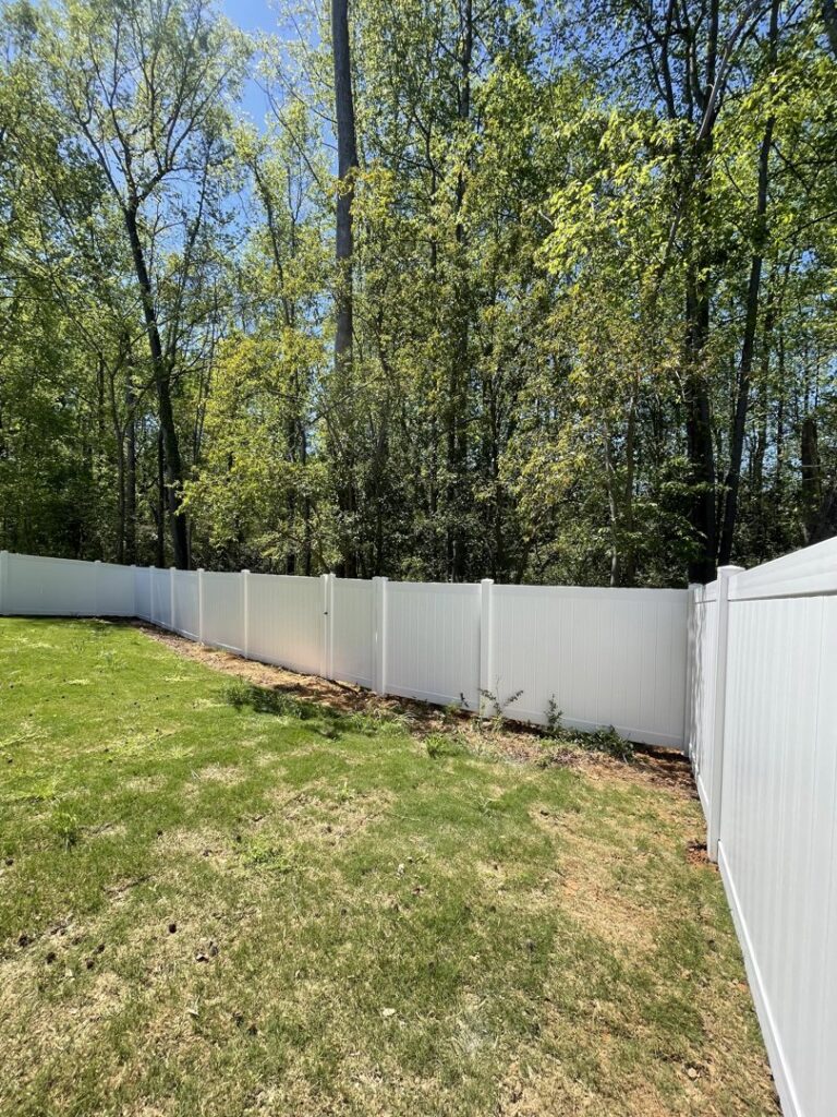 A long white vinyl privacy fence installed in a spacious backyard by RDU Fence in Holly Springs, NC.