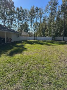 A long white vinyl fence enclosing a spacious backyard by Santis Fence & Home Service in Tampa Heights, FL