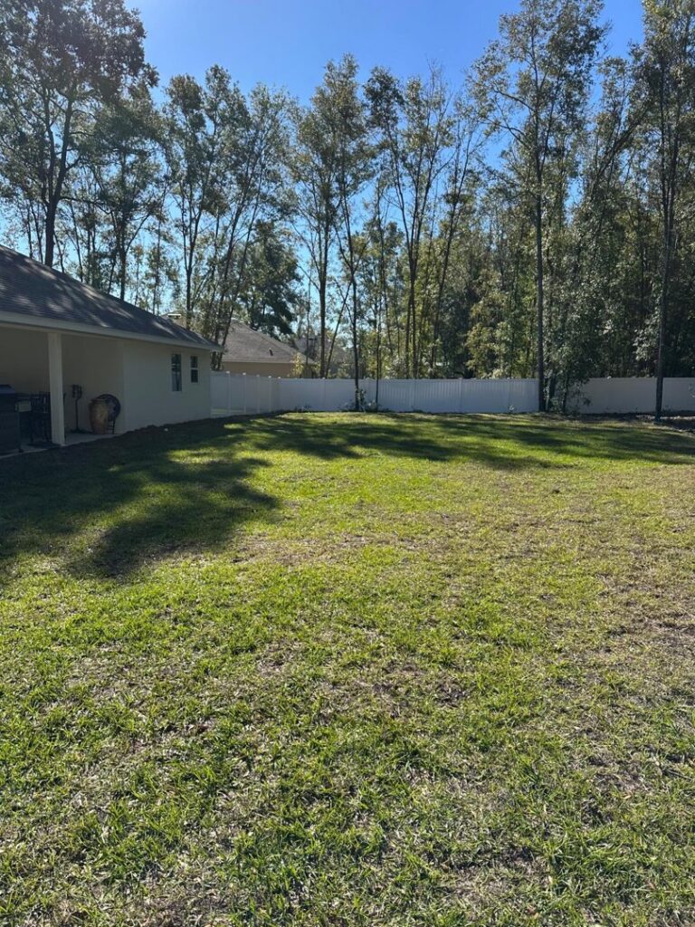 A long white vinyl fence enclosing a spacious backyard by Santis Fence & Home Service in Tampa Heights, FL
