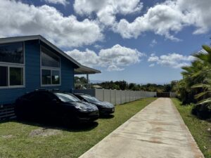 A long white vinyl fence installed along a residential driveway by Upright Fencing Hawaii LLC in Kapolei, HI.