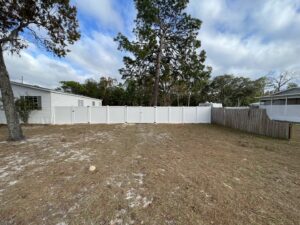 A long, newly installed white vinyl fence in a residential backyard by Aarons fence in Homosassa Springs, FL